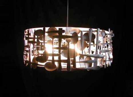 A circular lamp made out of spoons and forks crisscrossed over each other.