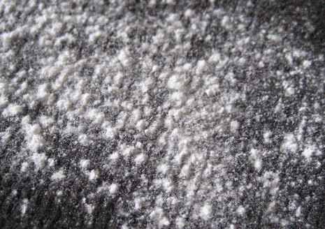 White powder dusted over a dark grey fabric.