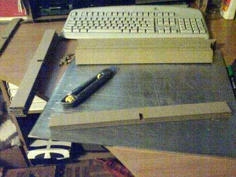 Keyboard and some wood pieces are arranging to make a cardboard furniture.