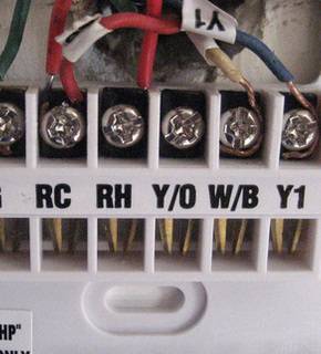 Backside of a thermostat with wires attached to the corresponding connections.