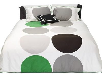 White bed with colorful round painting bedsheet.