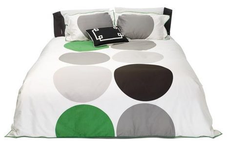 White bed with colorful round painting bedsheet.