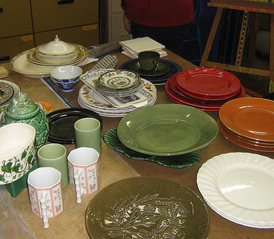 Dinning table with colorful plates, mugs and bowls.