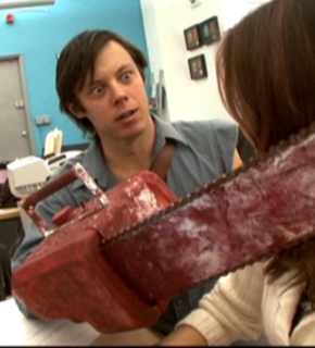 A man is holding an old red chainsaw near a woman.