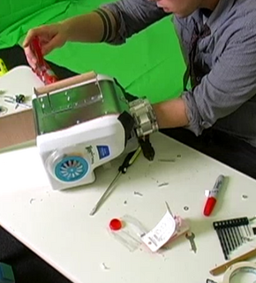 A person is using tools to work on something at a white table.