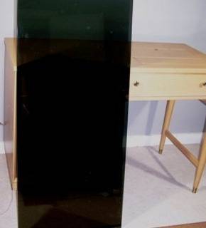 A black panel is standing vertically in front of a light colored desk.