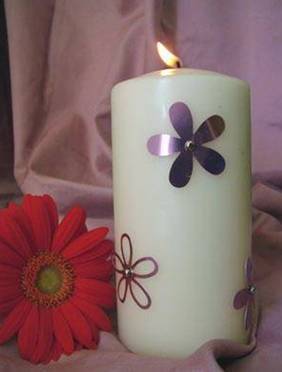 A white floral candle is burning.