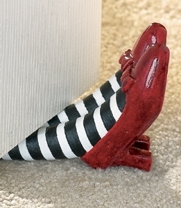 A door stop in the shape of two legs with black and white striped tights and red shoes.