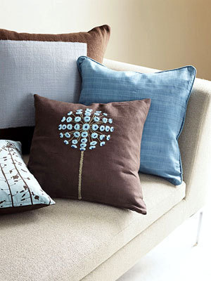 A variety of square decorative pillows in blue and brown on a pale sofa.