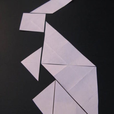 A rabbit has been made out of pieces of white paper on a black background.