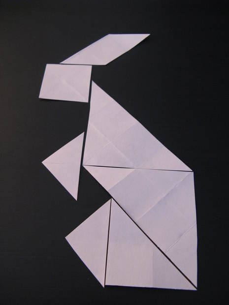 A rabbit has been made out of pieces of white paper on a black background.