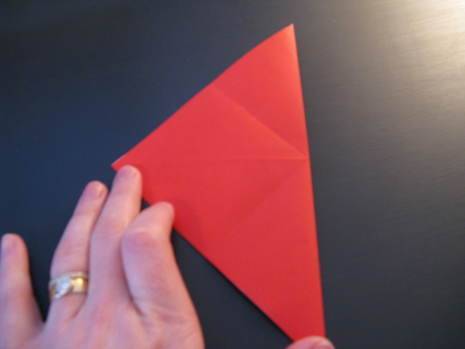 Red paper folded in half being touched by a hand with a ring on one of the fingers.