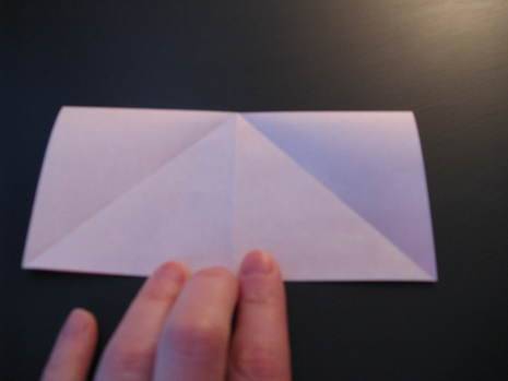 Man folding white paper to make origami heart envelope.