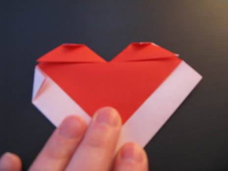 Man preparing origami heart envelope with color paper.