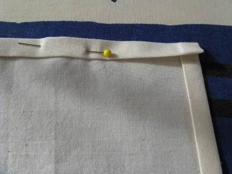Napkin is folded at edges and pinned with round headed pin.