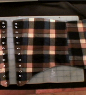 A plaid outfit with brown, pink and grey colors on a table.