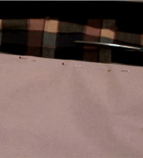 Scissors are cutting through a plaid material.