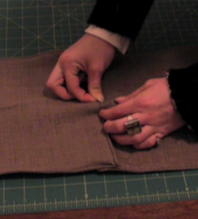 Folding and sewing a brown cloth.