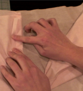 Folding a pink cloth with two hands.