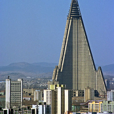 Pyramid shaped building with lightning bolt shaped sides, towering over a cityscape.