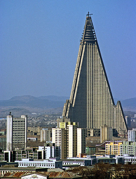 Pyramid shaped building with lightning bolt shaped sides, towering over a cityscape.