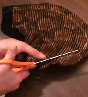 Someone using a piece if scissors to cut a piece of cloth