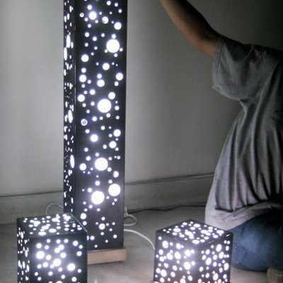 A person is touching a tall, three-piece decorative light.