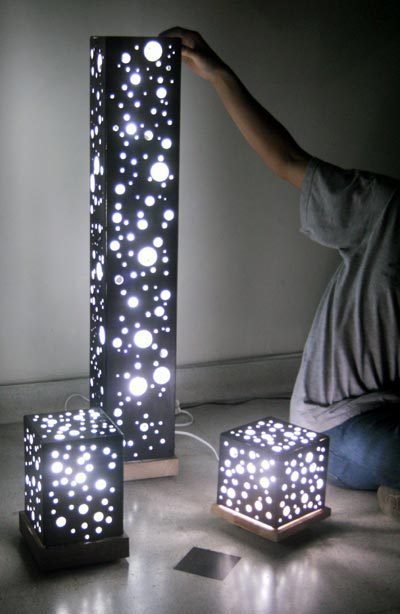 A person is touching a tall, three-piece decorative light.