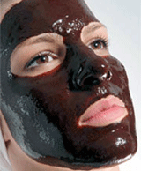 A woman relaxes with brown mask on her face.