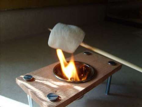 A person is roasting a marshmallow on a small roaster.