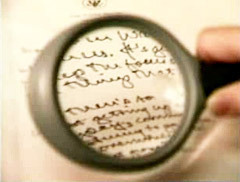 A person analysing handwriting with magnifying glass.