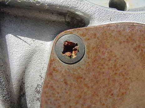 A screw on a metal plate is partially stripped.