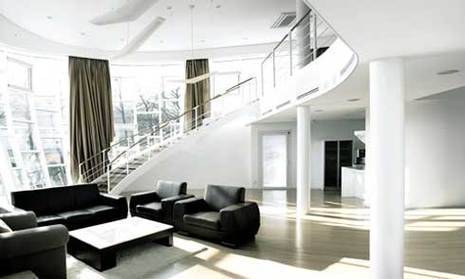 A stairway leads down to a living area with black furniture.
