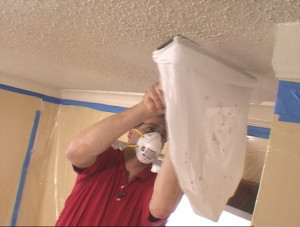 A man in a red shirt is working on the ceiling.