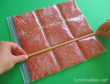 A ziplock bag full of meat or sauce, being sectioned off with a rod.