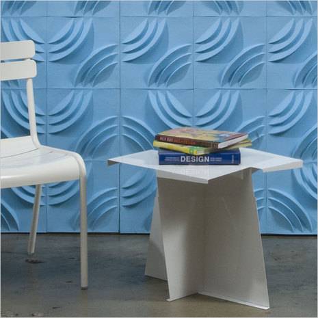 A white chair and table with books are sitting in a room with blue textured walls.