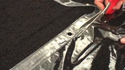 Black fabric with silver edges being pulled by a hand.