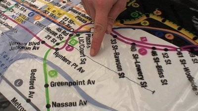 A subway rail line map that has a hand pointing to a spot.