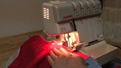 A person sewing a red piece of fabric.
