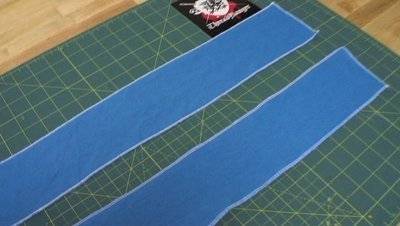 Two strips of blue cloth that is laid out on a green board.