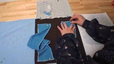 A person is working with blue material on a black surface.