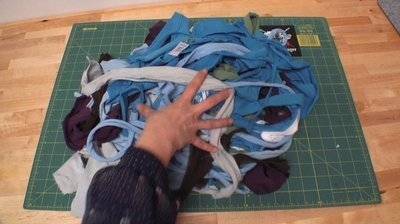 A person is grabbing at fabric scraps on a green grid.