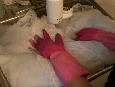 Hands with purple gloves touching a large plastic object in a sink.