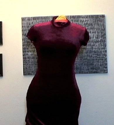 A purple dress is on a mannequin in from of a painting.