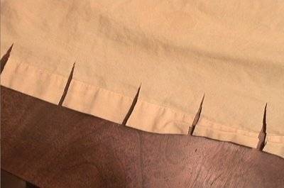 The edge of a piece of cloth with five small cuts along the edge.