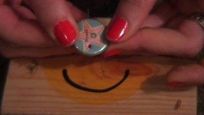 A bright blue button with a pink star being held with two hands.