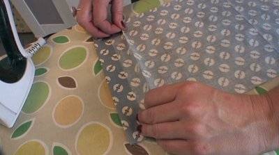 A person works with blue and white material on another green and yellow material.
