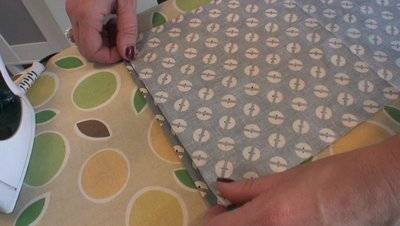 Two hands arranging a piece of blue patterned fabric.
