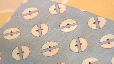 A blind hem along one edge of a gray fabric with a repeating half-circle geometric pattern.