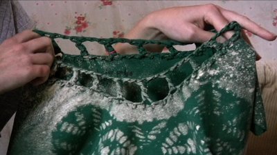 A hand knitted sweater that has a white and green design on it.